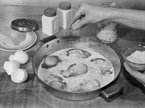 Woman Sprinkling Grated Cheese while Making Baked Eggs with Cheese, A Meat Substitute, Ann Rosener for Office of War Information, October 1942