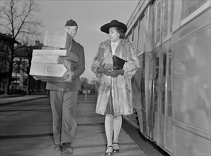Military Man Carrying Packages and Escorting Woman to her Home from Bus Stop now that Delivery of Goods have been Curtailed to Conserve on Tires and Gasoline during World War II, Ann Rosener for Offic...
