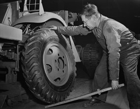 Worker Mounting a Wheel on Army's Half-Track Scout Car at Factory Converted to War Production, White Motor Company, Cleveland, Ohio, USA, Alfred T. Palmer for Office of War Information, December 1941