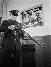 Sentinel Inspecting Rifle as he Keeps Vigil Against Saboteurs at Factory Converted to War Production, White Motor Company, Cleveland, Ohio, USA, Alfred T. Palmer for Office of War Information, Decembe...