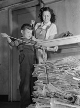 Mother Watching Young Son Tie up Large Bundle of Newspapers, as Conservation of Waste Paper will Save Millions of Dollars Annually for Uncle Sam during War Effort, Ann Rosener, Office of War Informati...