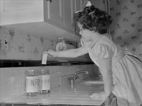 Young Girl Putting Empty Toothpaste Tube into Glass Jar, These Vital Tin and Alloy Metals Conserved by this Procedure will be Converted into Essential Products to Assist the War Effort, Ann Rosener, O...