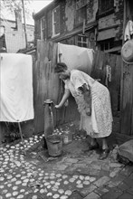 Woman Pumping Water in urban Backyard, Washington DC, USA, Carl Mydans for U.S. Resettlement Administration, July 1935