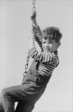 Portrait of Young Boy Hanging on Swing Chain at Playground, Child of Migratory Worker, Weslaco, Texas, USA, Arthur Rothstein for Farm Security Administration, January 1942