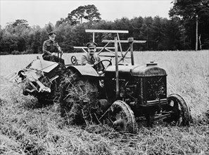Two Soldiers, Released for Temporary Emergency Farm Work, Operating Tractor and Harvester to cut Ten-Acre Field of Oats during Crop Season, which helped Ease Farm Labor Shortage during World War II, N...