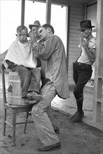 Boy Getting Haircut, Community Barber Shop, Migrant Camp, Kern County, California, USA, Dorothea Lange, Farm Security Administration, November 1936