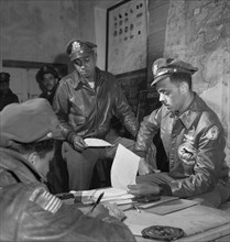 Tuskegee Airmen attending Briefing at Air Base, Woodrow W. Crockett, standing at center, Edward C. Gleed, Lawrence, KS, Class 42-K, Group Operations Officer, Seated on Right, and Unidentified Airman S...