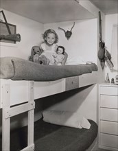Young Girl with Stuffed Animal and Toy Doll, Sitting on Top Bunk Bed in Children's Bedroom, 1946