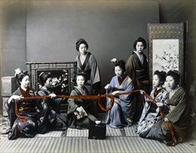 Japanese Women Holding Fabric Tied in a Knot, Hand Colored Albumen Photograph, circa 1870