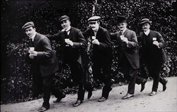 Five Men Holding Beer Glasses While Walking Single File With Hands Touching Shoulders, Germany, 1910