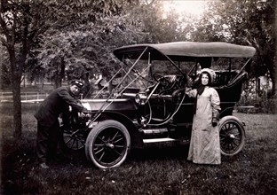 Woman Standing Beside Maxwell Touring Car and Driver Cranking Engine, USA, 1908