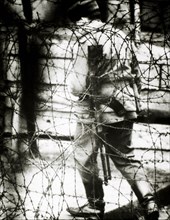 East German Border Guard Viewed Through Barbed Wire Fence, 1965