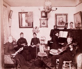 Family Sitting in Parlor While One Person Plays Piano and One Plays Guitar, USA, circa 1890