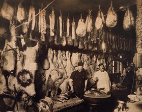 Two Butchers Standing in Front of Large Display of Meat, circa 1910
