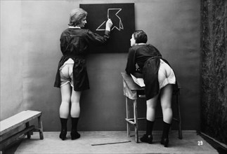 Two Scantily-Clad Women with Backsides Exposed in Classroom, circa 1910's