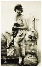 French Lingerie Model Seated on Edge of Bed Holding Cat, circa 1920