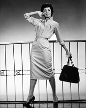 Female Model Posing in Fashionable Dress and Holding Handbag, circa 1950