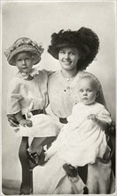 Woman With Dark Hat Seated with Two Children, one with Hat, Portrait, circa 1915