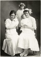Two Seated Women Holding Newborn Infants with Young Girl Standing in Rear, Portrait, circa 1920