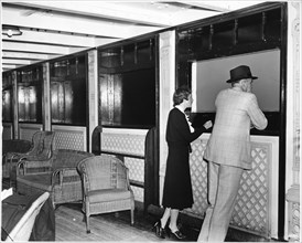 Two Passengers Looking out Open Window of Ocean Liner upon Arrival in New York City, USA, While other Windows are Painted Black to Keep the Ship Unseen due to Pending War Crisis in Europe, August 1939