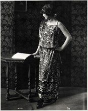 Fashionable Woman in Dinner Dress of Silk Crepe and Satin with an Embroidered Design of Tropical Birds, and Hat, Portrait, circa 1922