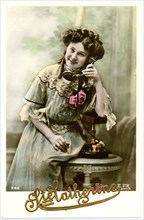 Smiling Woman in Light Blue Dress Sitting on Table Holding Telephone, French Postcard, circa 1911