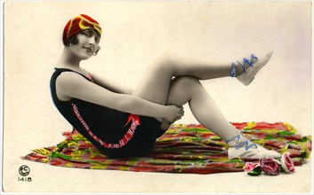 Seated Woman on Colorful Blanket Wearing Dark Swimsuit and Red Cap, Holding Thighs, Hand-Colored, French Postcard, circa early 1900's