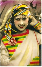 Smiling Woman in Beige Dress with Colorful Bands and Head Scarf, Hand-Colored French Postcard, circa 1915