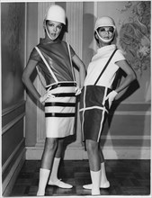 Two Fashion Models Wearing Sleek Interpretations of Andre Courreges’ Suspender Outfits Featuring Barrel Skirts with Button-Attached Suspenders and Leather Cowl-Neck Blouses, Presented by Samuel Robert...
