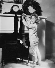 Shirley Temple, Publicity Portrait Hanging Christmas Stocking on Mantel, 1934