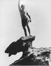 Actor Fredric March Standing on Rock Formation in Bathing Suit, Low Angle View, California, USA, early 1940's