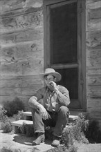 Cowboy Smoking in front of Bunkhouse, Quarter Circle U Ranch, Big Horn County, Montana, USA, Arthur Rothstein, Farm Security Administration, June 1939