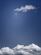 Moon and Clouds Against Blue Sky