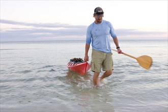 Man Pulling Kayak onto Beach, Florida Keys, USA