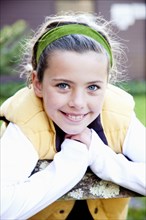 Smiling Girl With Green Headband Leaning on Fence