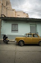 Yellow Car and Motorcyle Parked in Front of Teal House, San Gil, Colombia