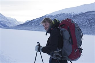 Smiling Young Man Backpacking in Winter Landscape