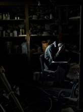 Man Sitting in Dark Basement