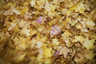 Girl Covered in a Pile of Autumn Leaves