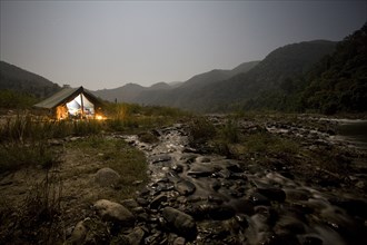 Illuminated Camp Site by Stream in National Park