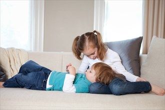 Young Boy Laying in Sister's Lap on Sofa