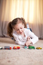Girl Playing on Floor with Toy Cars and Trucks