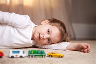 Girl Portrait on Floor with Toy Cars and Trucks