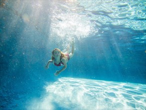 Girl Swimming Underwater in Pool, Looking Up