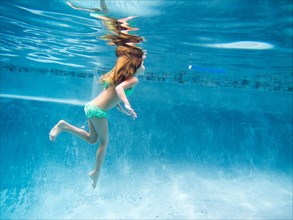 Girl Floating Underwater in Pool Just Below Surface