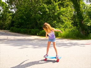 Young Girl Riding Skateboard in Street