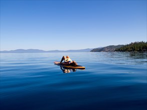 Woman Laying Down on Paddleboard on Lake