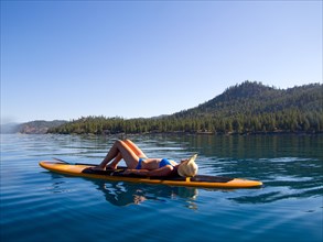 Woman Laying Down on Paddleboard on Lake 4