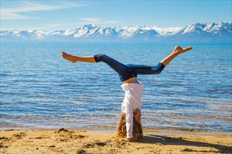 Young Girl Doing Hand Stand on Beach with Sierra Mountains in Background, Lake Tahoe, Glenbrook, Nevada, USA