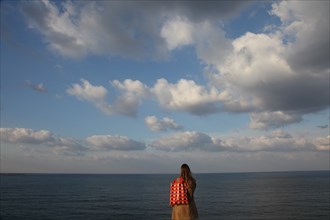 Young Woman on Beach Looking at Horizon, Rear View